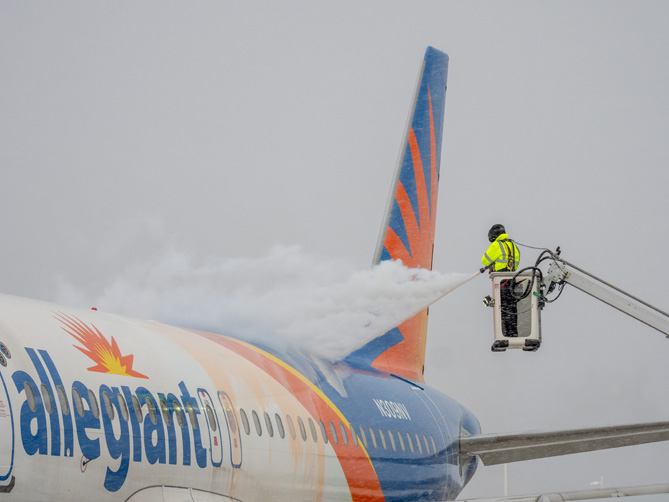Photo of airline employee de-icing an airplane